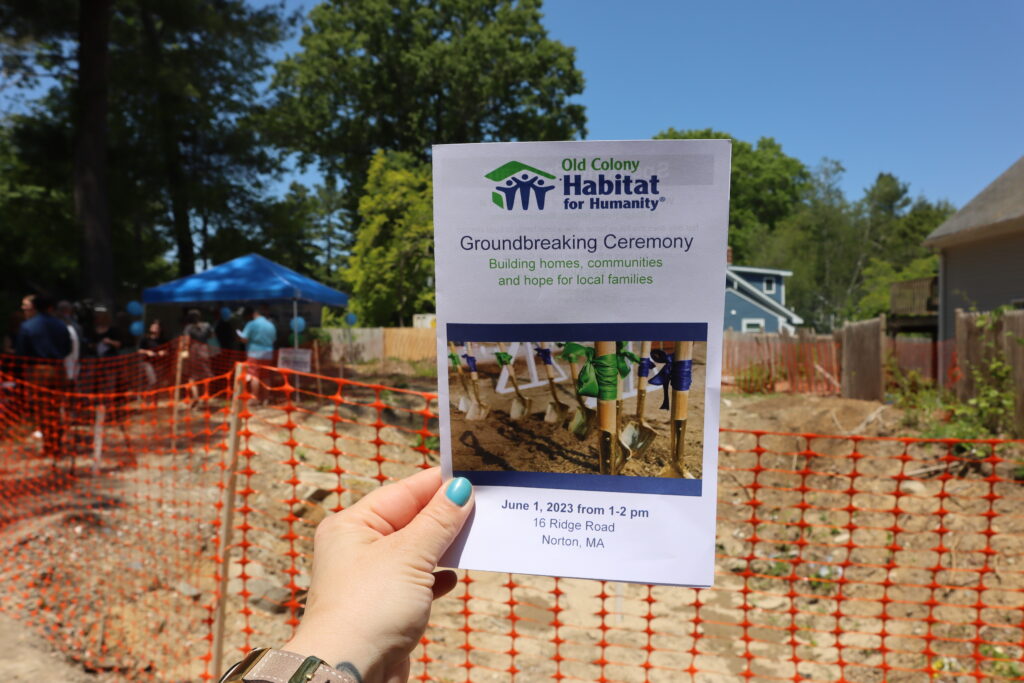 El programa de la ceremonia de colocación de la primera piedra de Hábitat para la Humanidad frente a las obras.